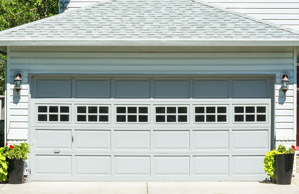 Wide garage door of residential house with concrete driveway in front